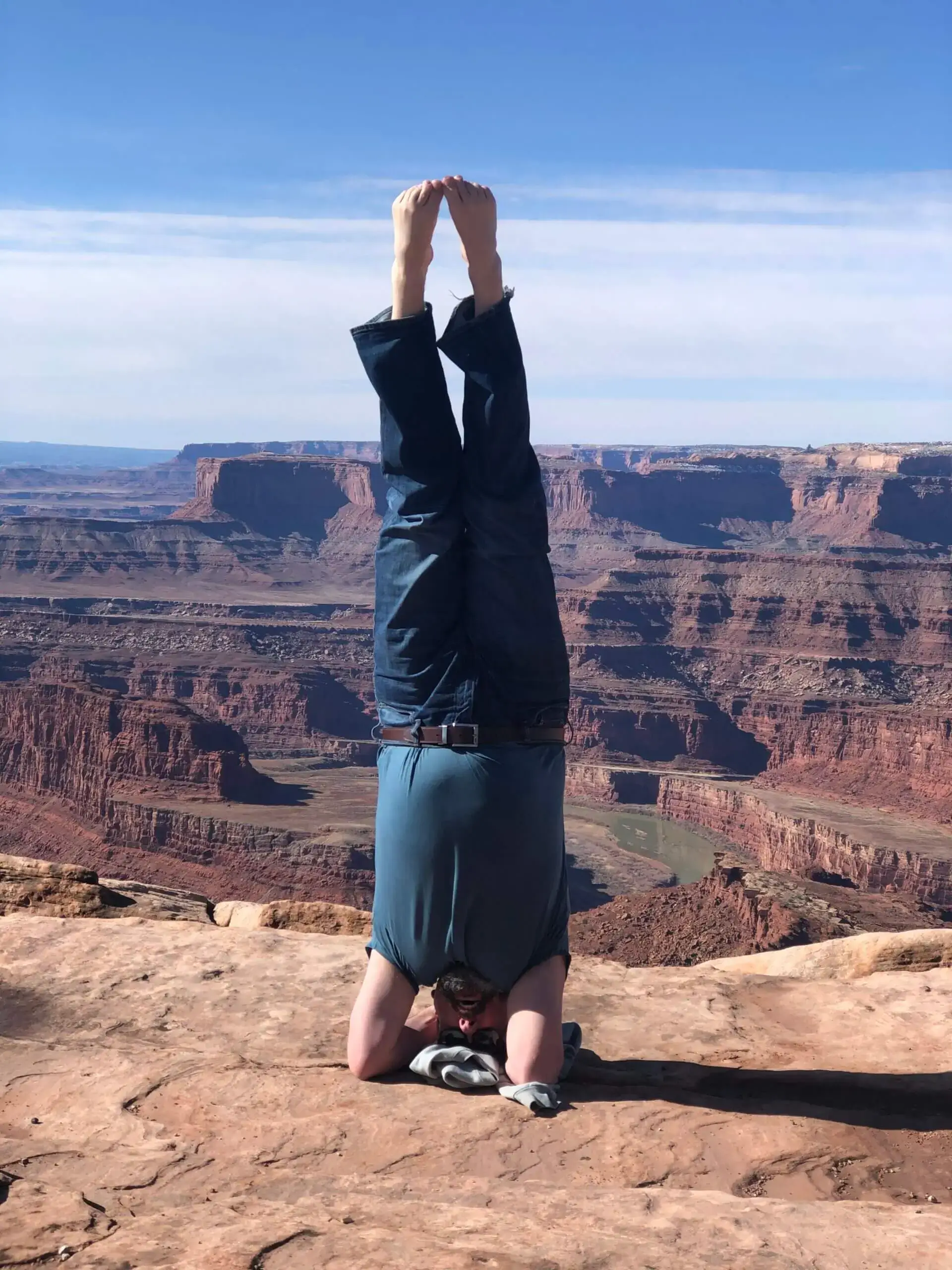 Person doing a headstand on a cliff overlooking a canyon.
