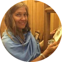 A woman smiling while holding a book indoors.